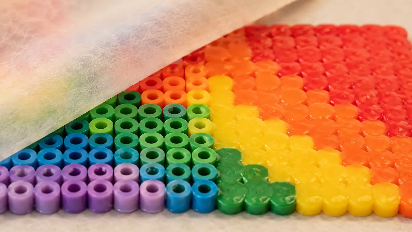 Close-up comparison of visible bead holes and fully melted Perler beads during ironing